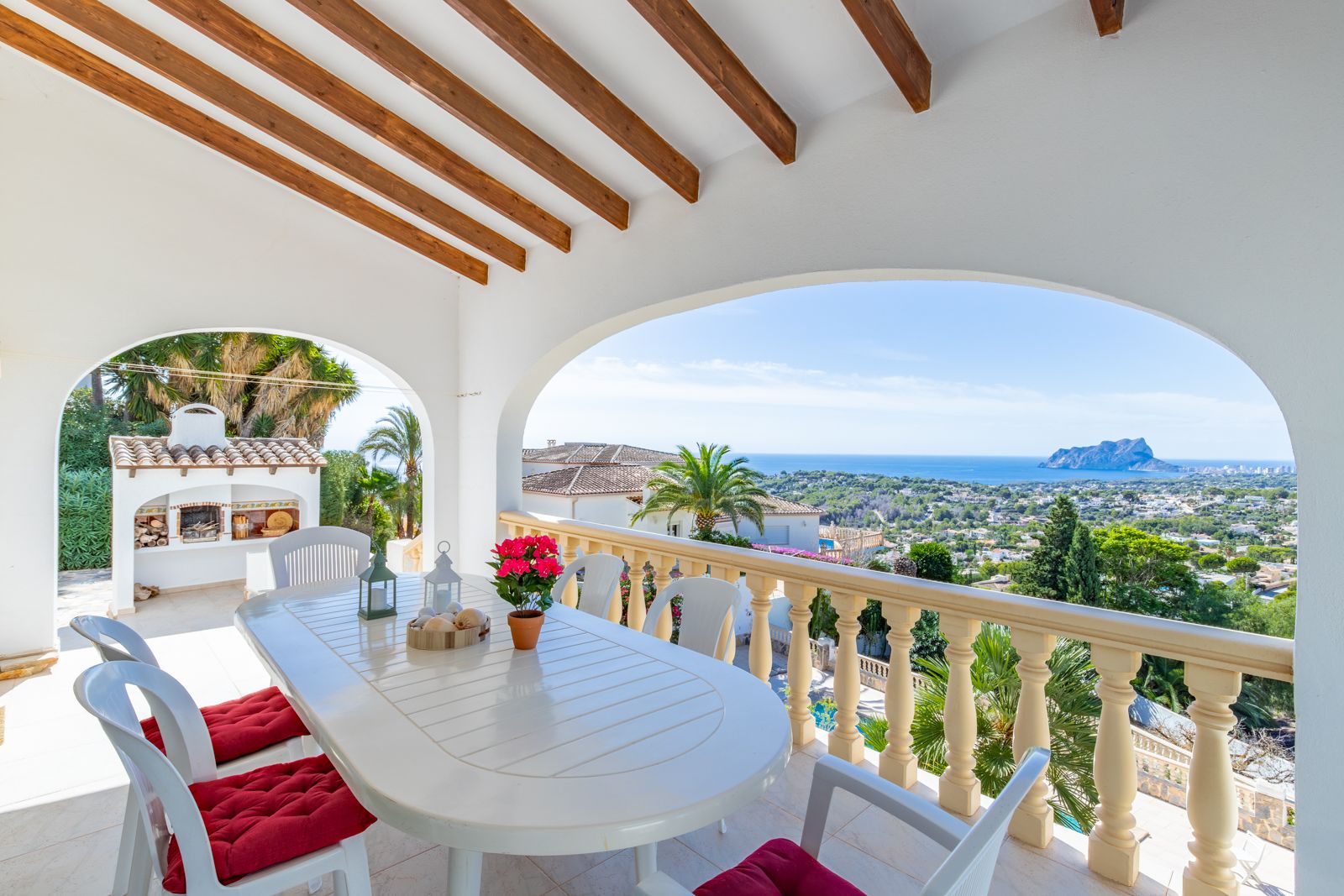 Covered terrace featuring wooden ceiling beams, an outdoor dining set, and panoramic views of the Mediterranean Sea and Peñón de Ifach.