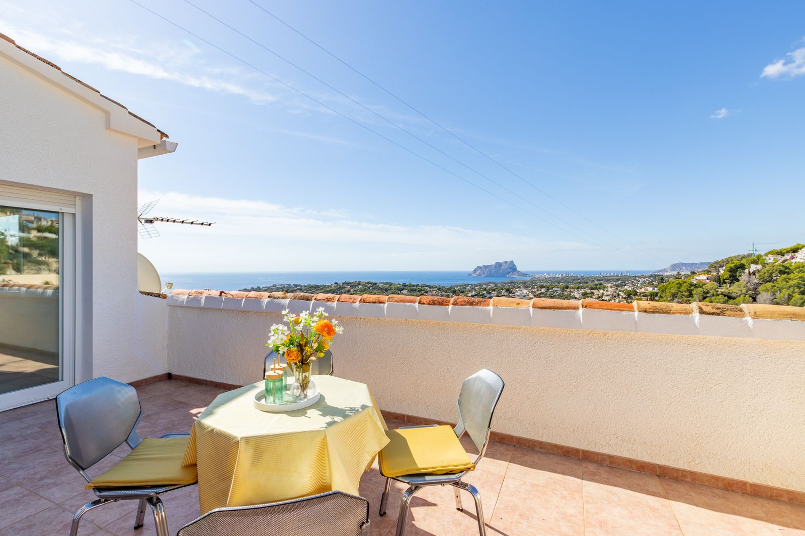 Elevated terrace featuring ceramic tiling and panoramic views of the Mediterranean Sea and Peñón de Ifach, complete with an outdoor seating area.