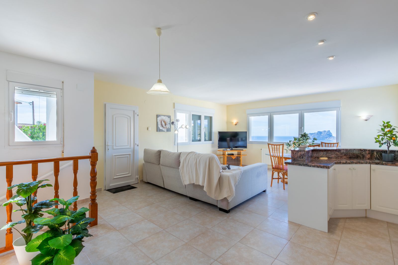 Open-plan living and dining area featuring a kitchen with granite countertops and large windows offering views of the Mediterranean Sea and Peñón de Ifach.