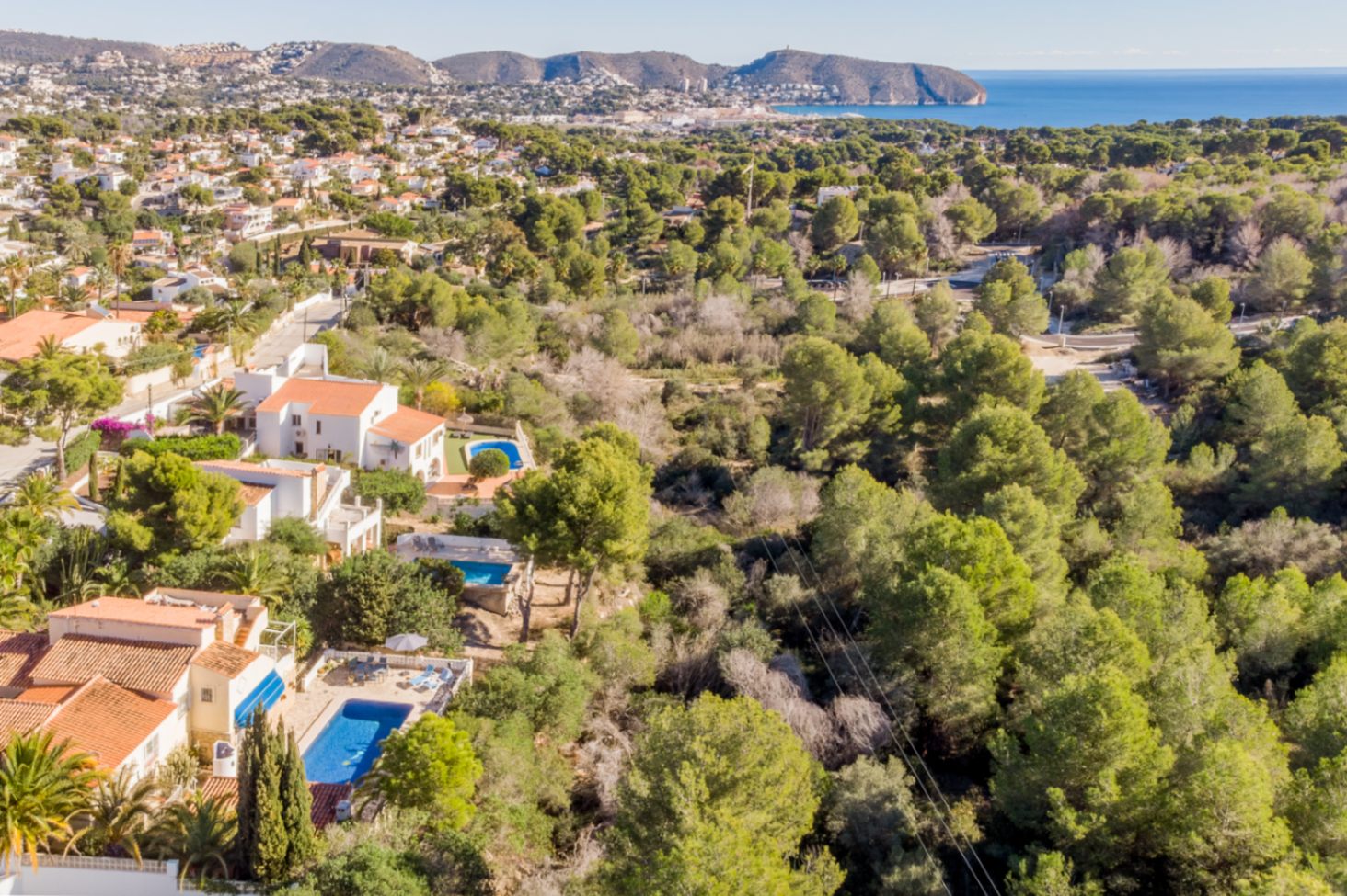 Aerial view showcasing the prime location adjacent to a protected green zone, offering panoramic views of the Mediterranean Sea and the Moraira coastline.