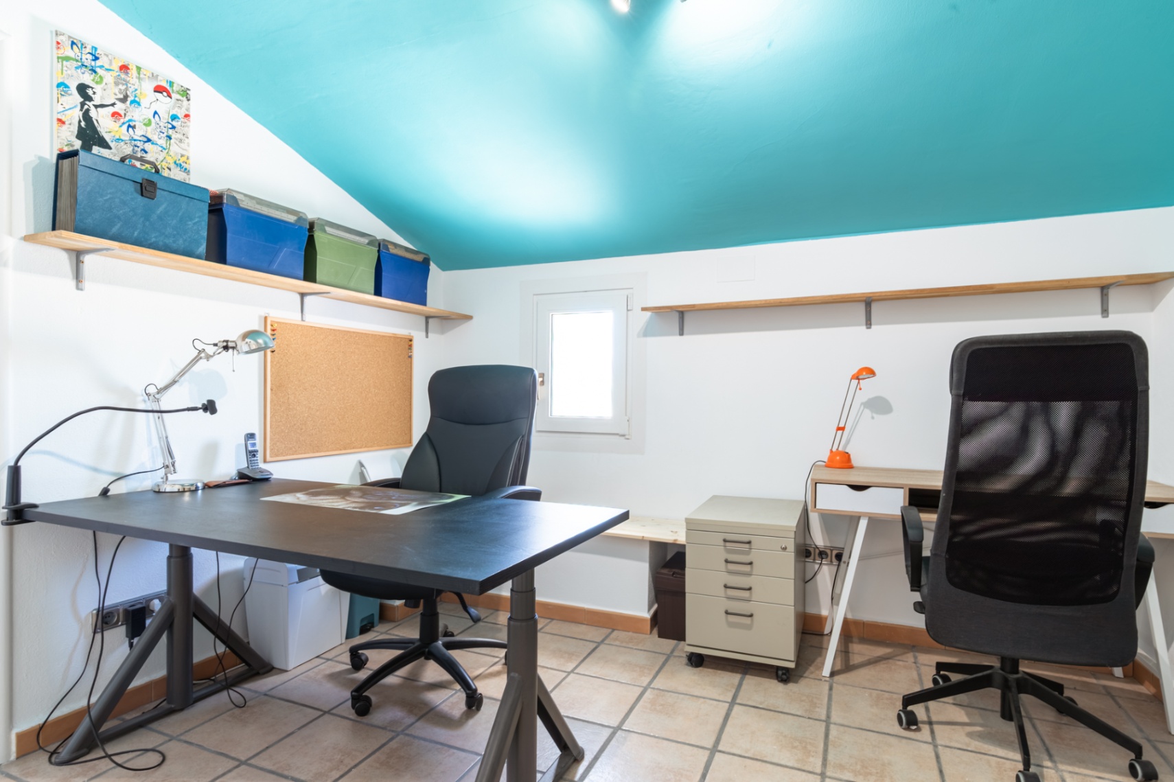 Functional home office featuring a distinctive turquoise sloped ceiling, dual workstations, ceramic tile flooring, and integrated wall shelving.