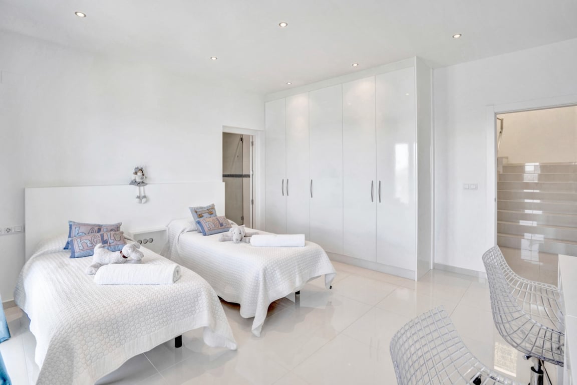 Minimalist double bedroom featuring high-gloss built-in wardrobes, white polished flooring, and integrated recessed ceiling lighting.