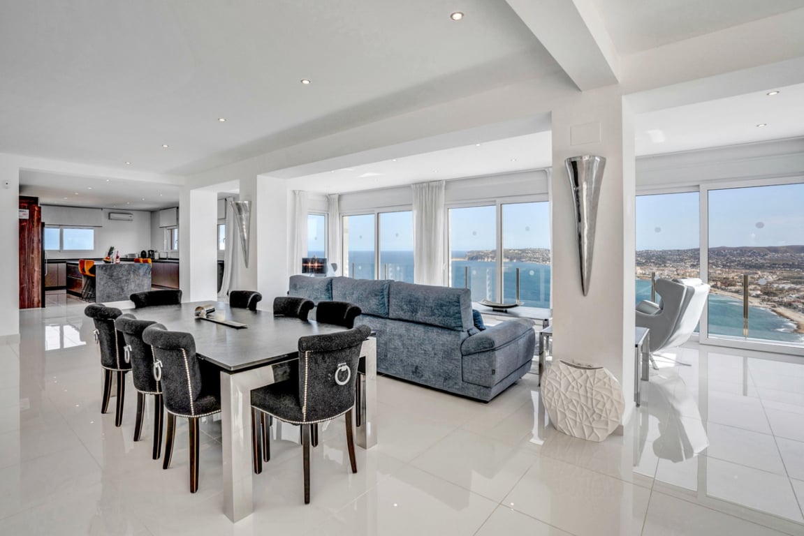 Open-plan living and dining area featuring polished floors, contemporary furniture, and floor-to-ceiling windows with panoramic Mediterranean Sea views.