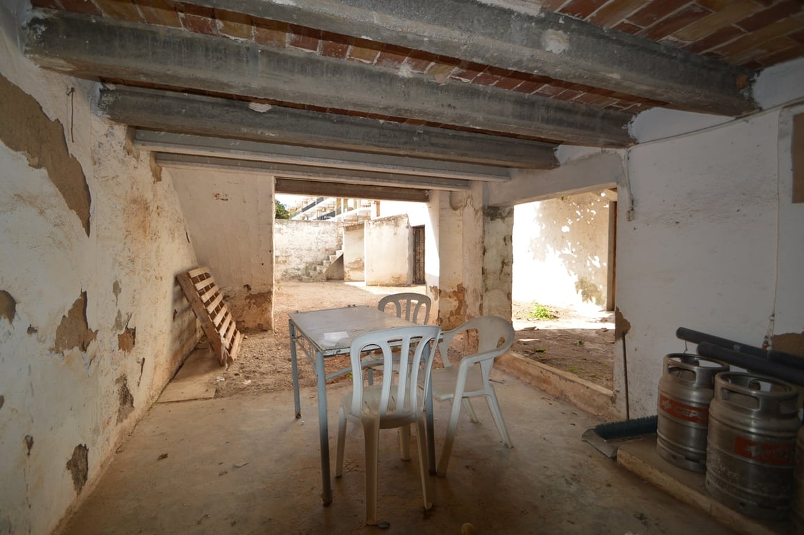 Covered porch area featuring exposed concrete beams and brickwork, offering direct access to the private walled garden and patio.