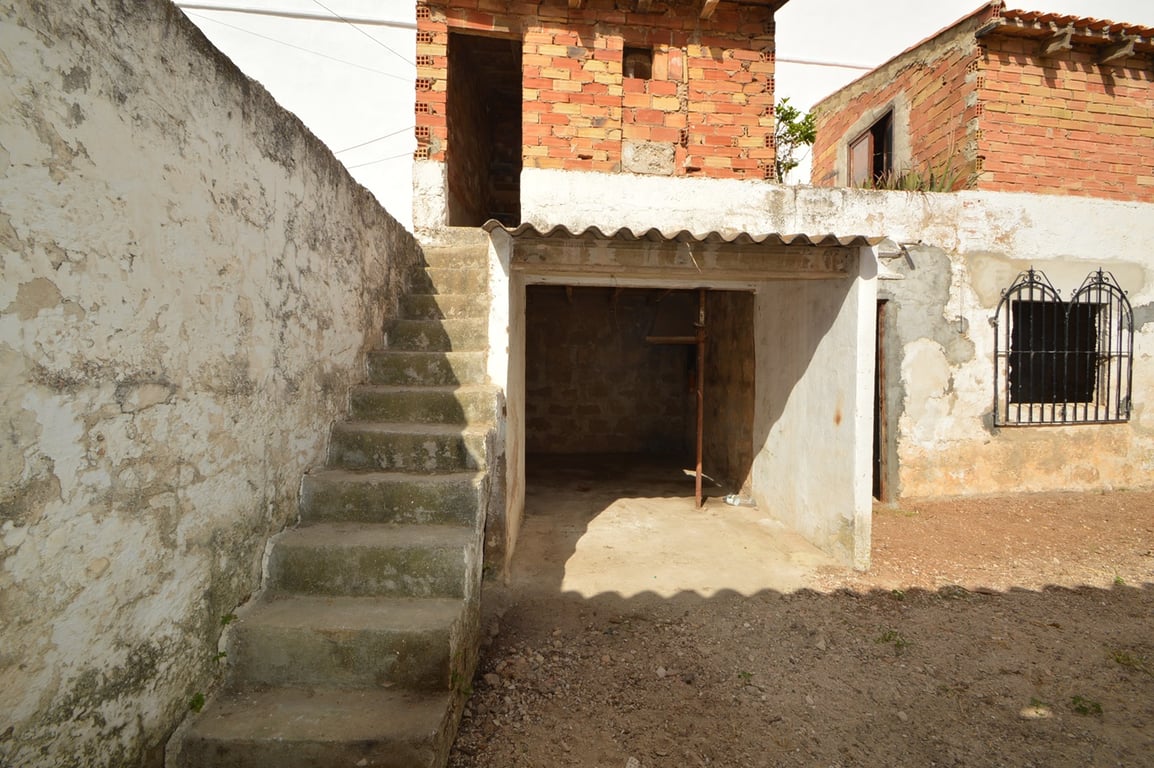 Exterior patio featuring concrete stairs, a covered storage area, and exposed brick structures awaiting renovation in the historic center.