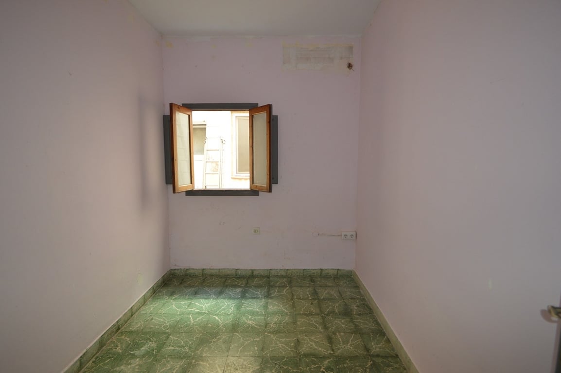 Interior room featuring green marbled floor tiles, light mauve walls, and a traditional wooden window opening towards the inner courtyard.