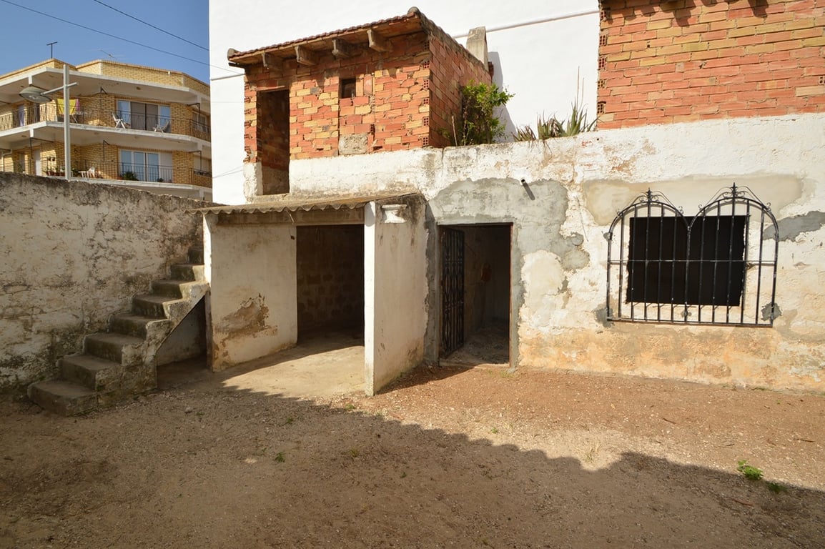 Internal courtyard featuring exposed brickwork, a stone staircase, and versatile outbuildings ideal for conversion into a studio or storage space.