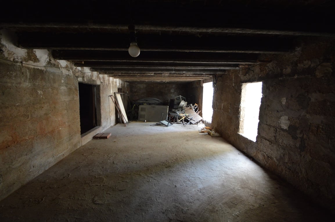 Spacious open area featuring exposed wooden ceiling beams and original stone walls, offering significant potential for a studio or storage room conversion.