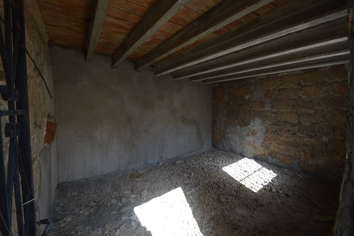 Spacious raw storage area featuring original stone walls, exposed ceiling beams, and natural light, offering potential for conversion into a studio.