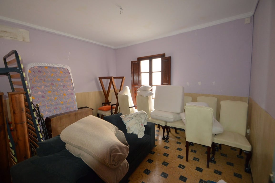 Spacious room featuring lavender walls with wood wainscoting, traditional patterned tile flooring, and a classic wooden window with interior shutters.