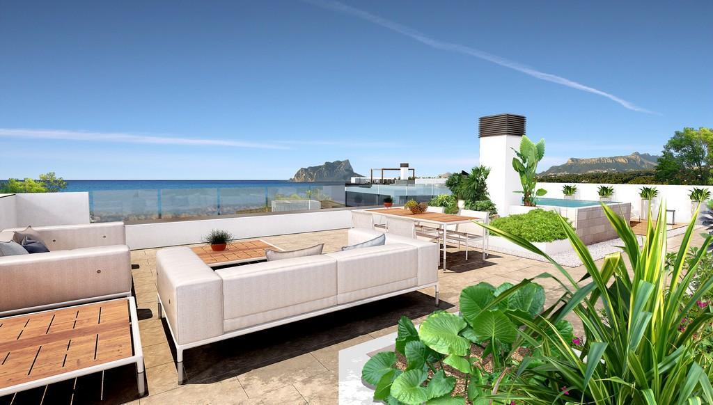 Rooftop solarium featuring a lounge area, outdoor dining, and glass railings with panoramic views of the Mediterranean Sea and Peñón de Ifach.