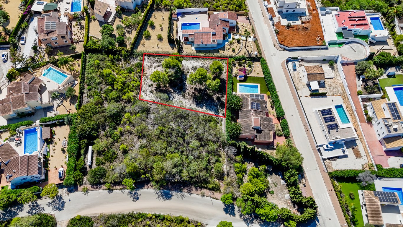 Aerial perspective highlighting the adjacent building plot outlined in red, positioned next to the villa featuring a private pool and rooftop solar panels.