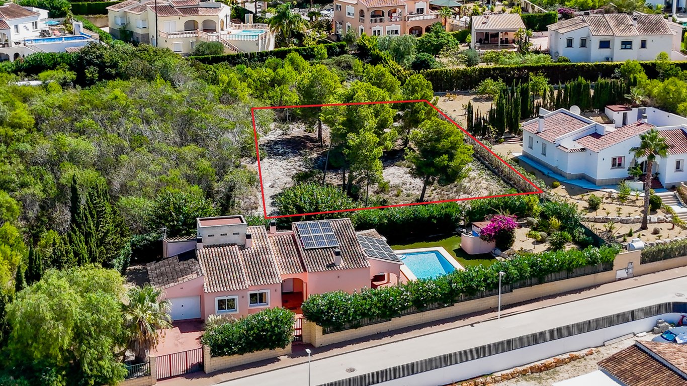 Aerial view of the villa featuring solar panels and pool, with the adjacent urban building plot clearly outlined in red.