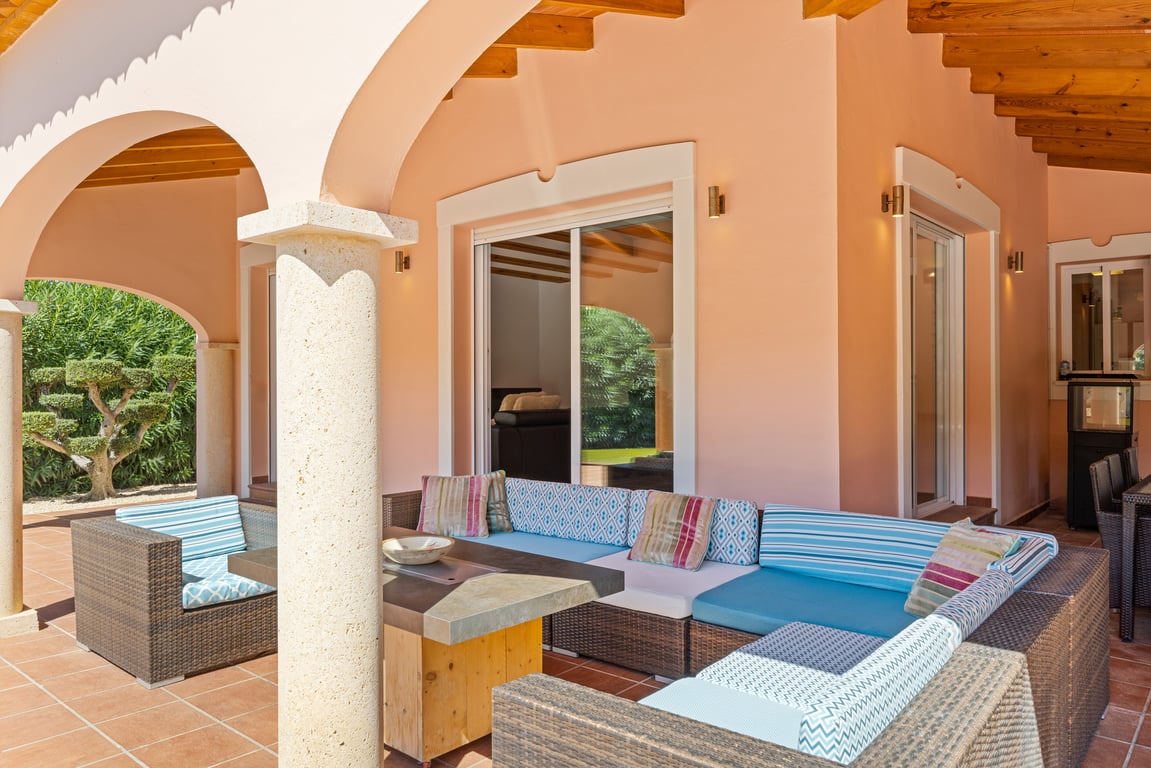 Covered naya featuring traditional stone arches, exposed wooden beams, and a lounge area with wicker furniture on terracotta tiling.