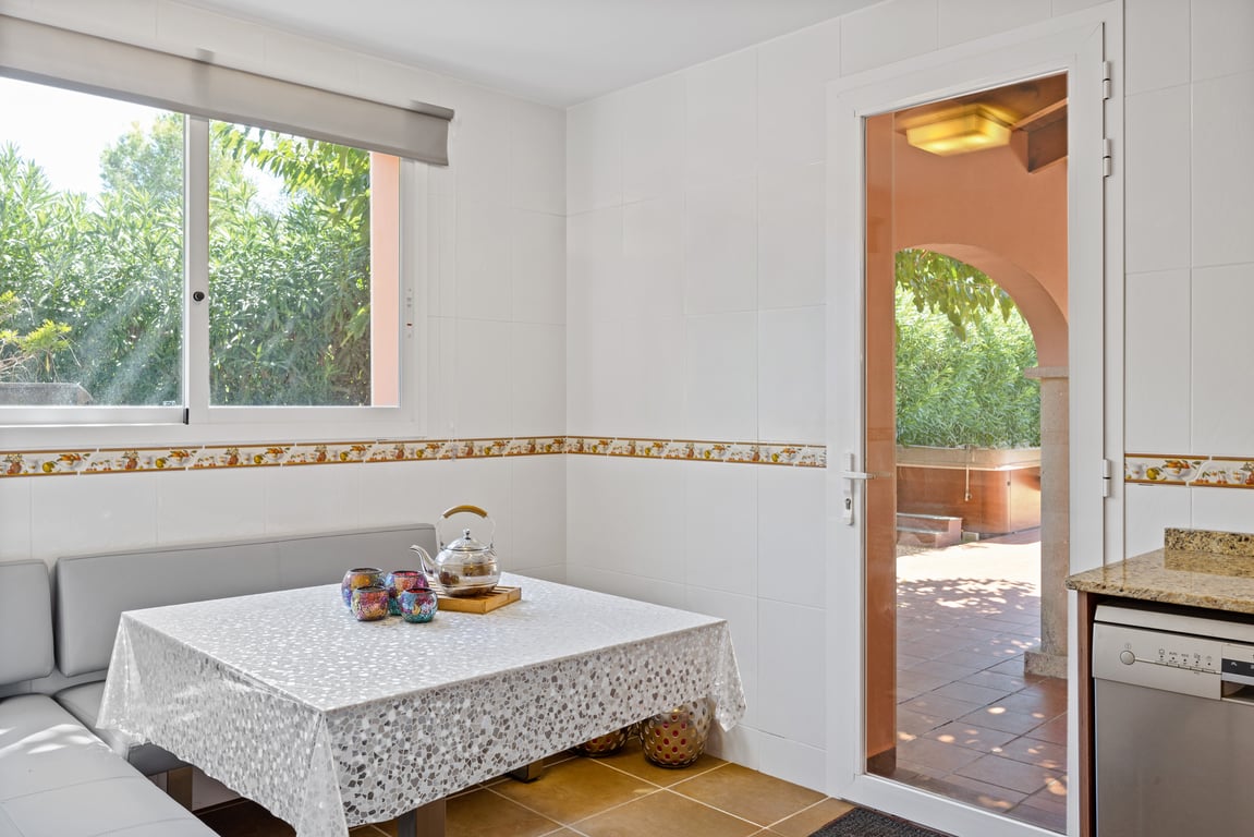 Kitchen breakfast area featuring a built-in bench, tiled walls, and a glass door providing direct access to the arched terrace and outdoor space.