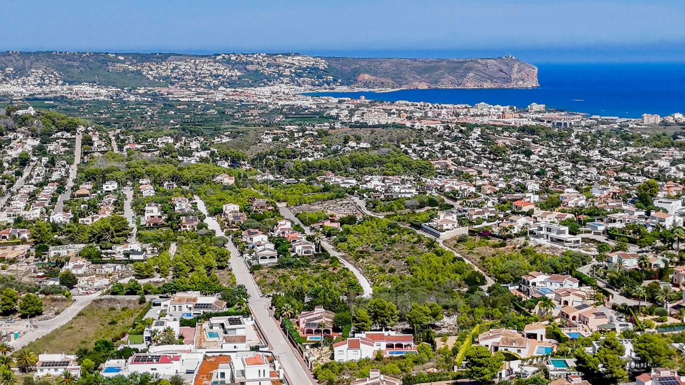 Panoramic aerial view of Jávea showcasing the proximity to the Mediterranean Sea, Cabo de San Antonio, and residential areas nestled in Mediterranean greenery.