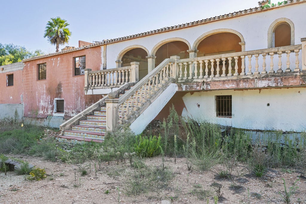 Exterior facade featuring a grand stone staircase with decorative tiles leading to an arched terrace and traditional Mediterranean balustrade.