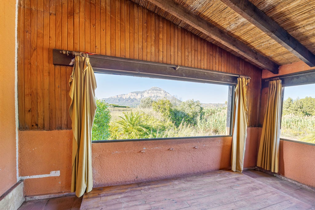 Interior space featuring wooden paneling and a cane ceiling, offering framed views of the Montgó mountain through a wide horizontal window.
