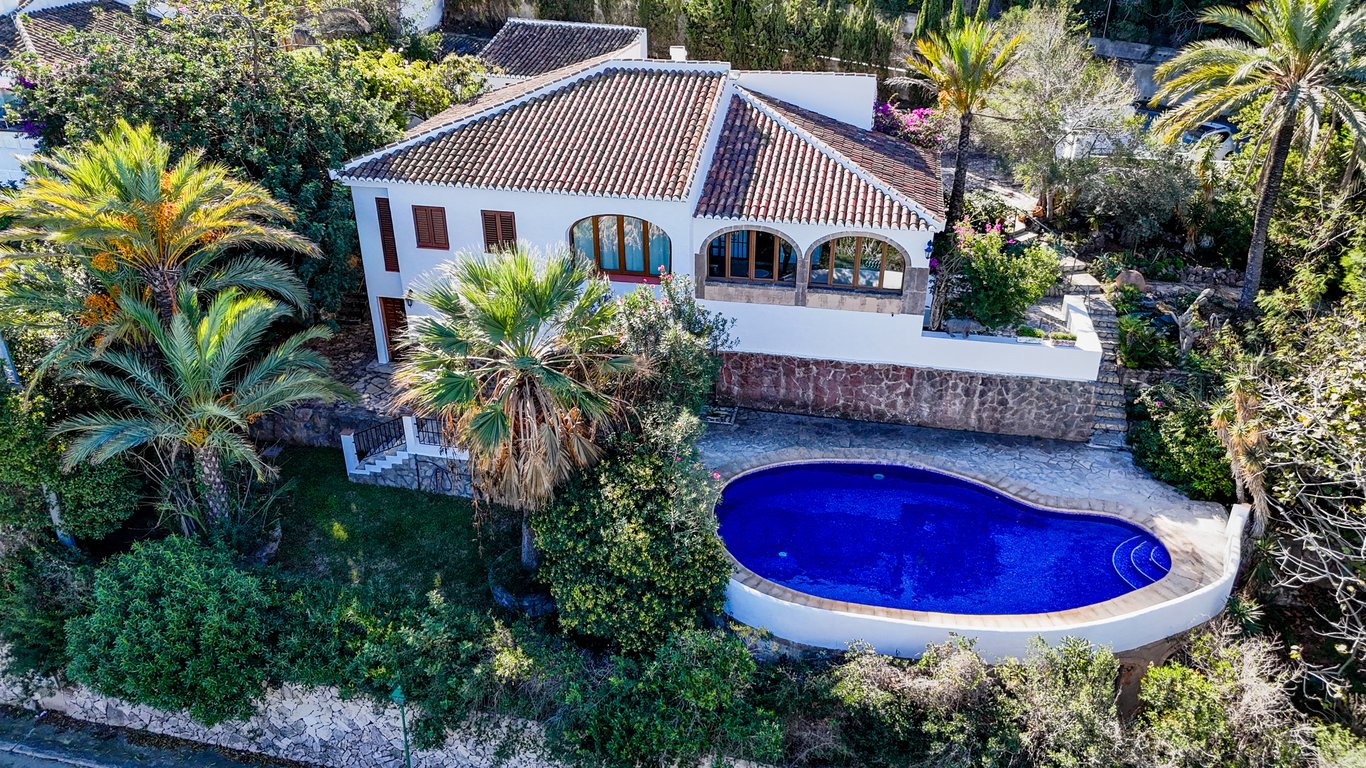 Aerial view of the traditional villa featuring a kidney-shaped pool, stone terraces, and a classic naya with authentic Tosca stone arches and terracotta roofing.