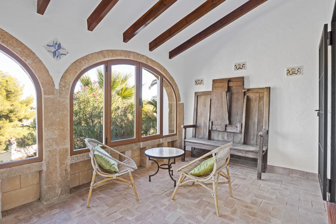 Enclosed naya featuring authentic Tosca stone arches, exposed wooden beams, and traditional ceramic tiling. Includes rustic seating with views of the Mediterranean greenery.
