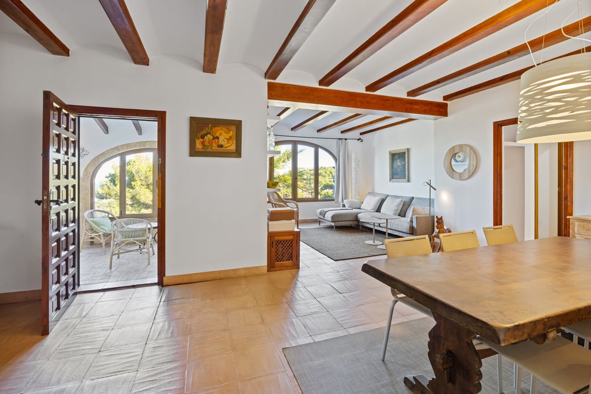 Traditional living and dining space featuring exposed wooden beams, handmade terracotta tiles, and access to a covered naya with Tosca stone arches.