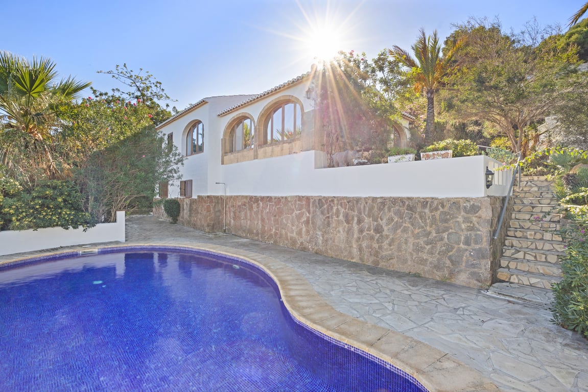 Villa exterior featuring a private pool, natural stone retaining walls, and a traditional naya with Tosca stone arches.