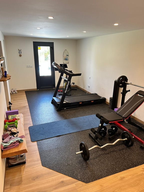 Private home gym featuring a treadmill, weight bench, and yoga area, with wood-effect flooring, recessed lighting, and direct outdoor access.
