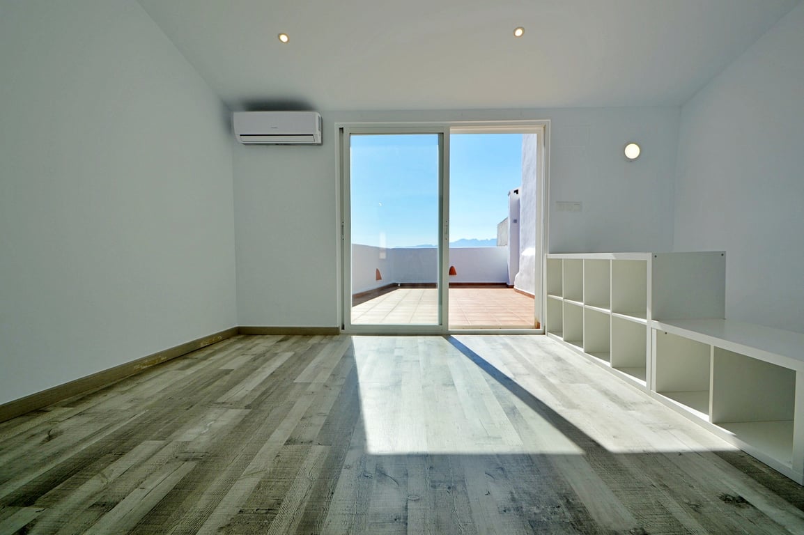Bright interior space featuring wood-effect flooring, air conditioning, and sliding glass doors opening onto the spacious sun terrace.