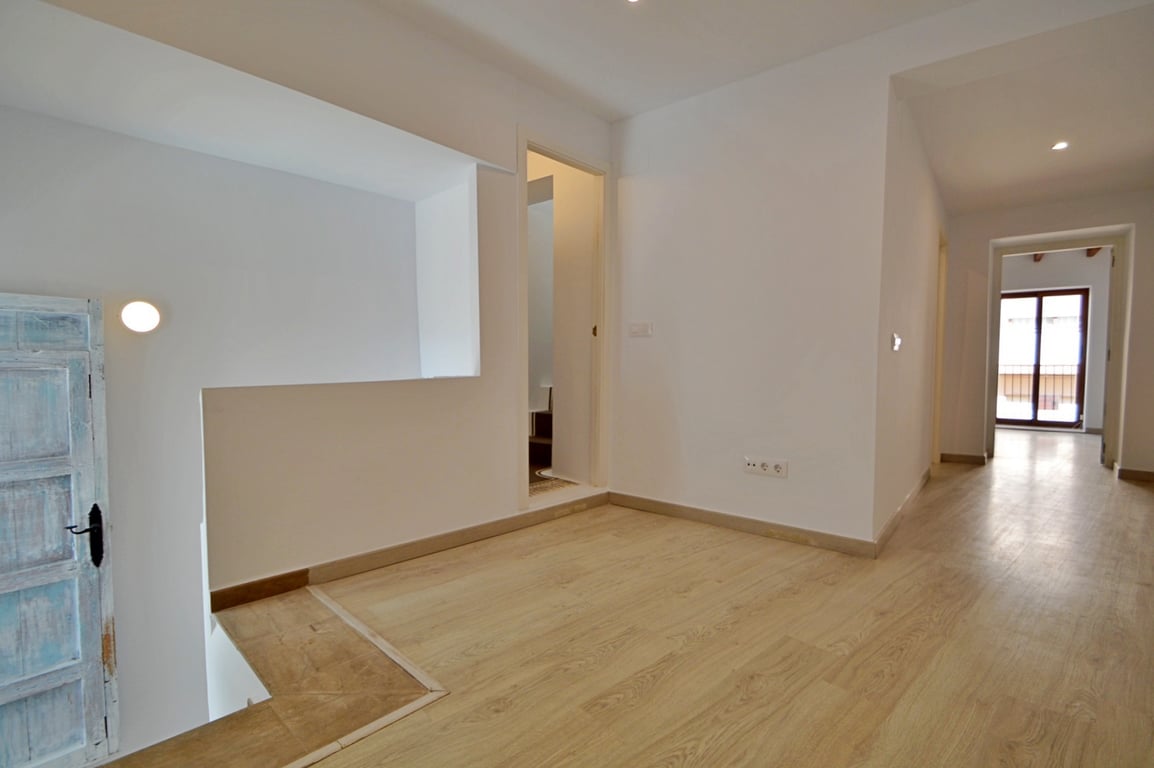 Bright landing featuring light wood flooring, minimalist white walls, and a restored rustic blue door leading to the upper floor hallway.