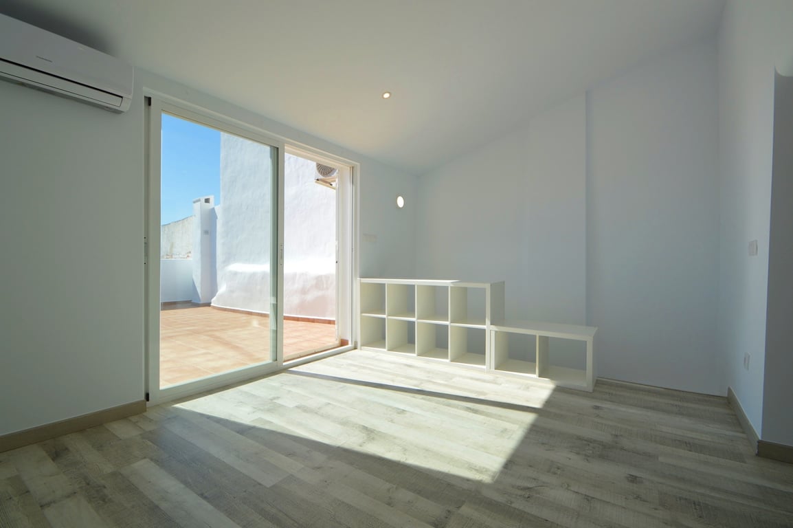 Bright room featuring light wood-effect flooring, split-system air conditioning, and direct access to a tiled terrace through large sliding glass doors.