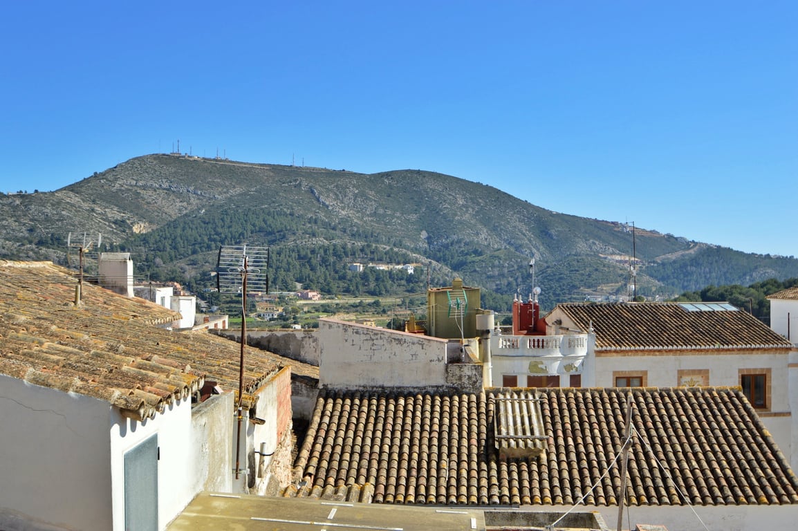 Panoramic mountain views from the rooftop terrace, overlooking traditional terracotta tiled roofs and the local landscape.