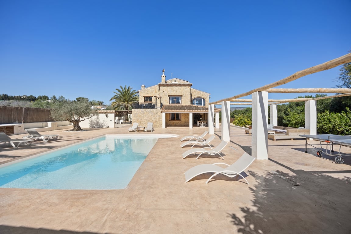 Exterior view of the stone-clad villa featuring a 5x10m swimming pool, spacious sun terrace with loungers, and a pergola-shaded area with a table tennis table.