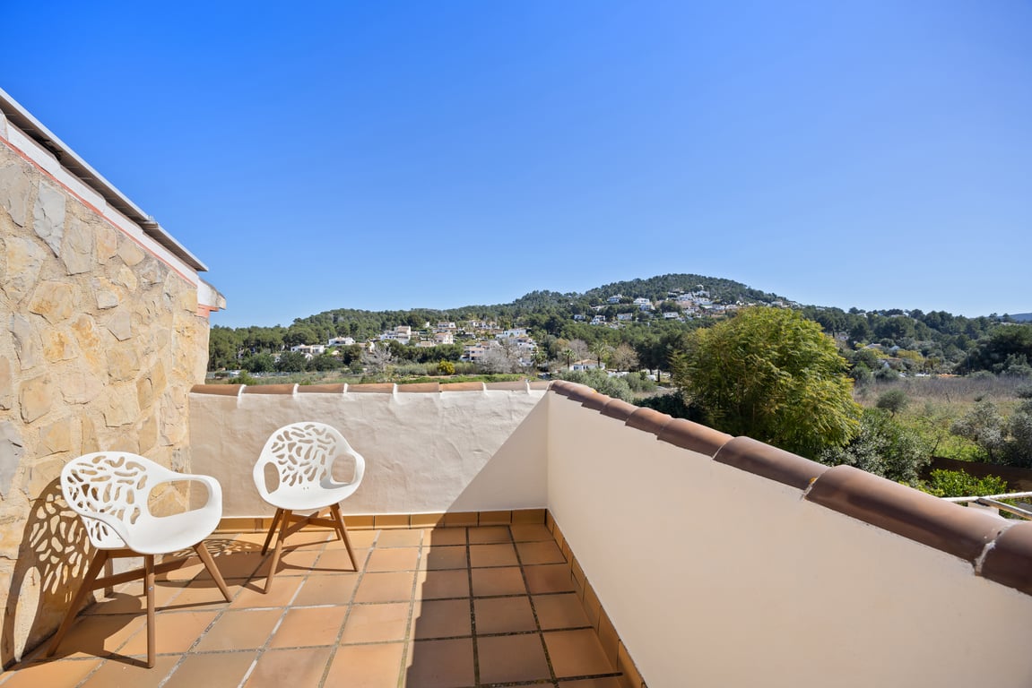Private upper-level terrace featuring terracotta tiling, modern seating, and panoramic views of the lush green hills and Mediterranean landscape.