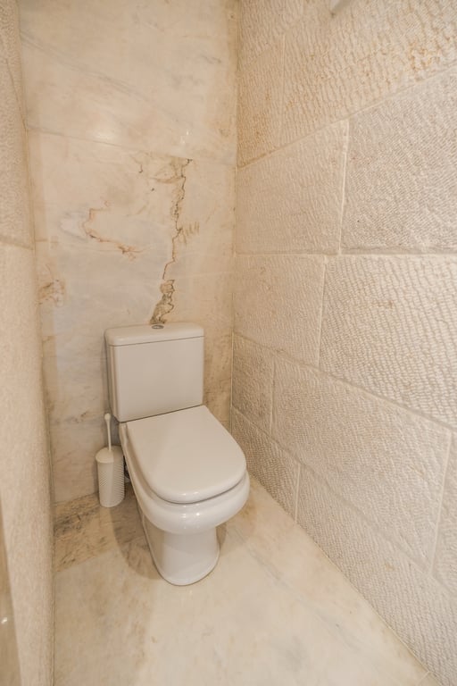 Bathroom featuring textured limestone walls and polished marble finishes, blending natural materials with modern fixtures.