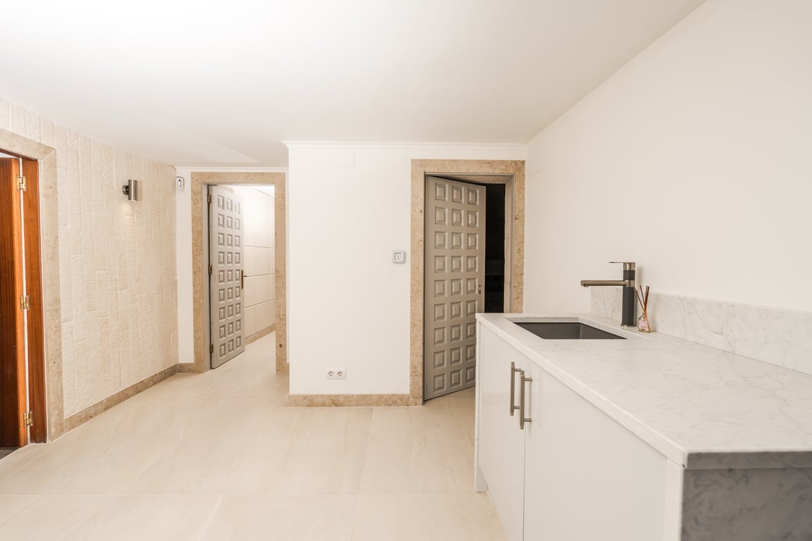 Functional hallway area with marble countertop and integrated sink. Features natural stone door frames and decorative grey doors against light flooring.