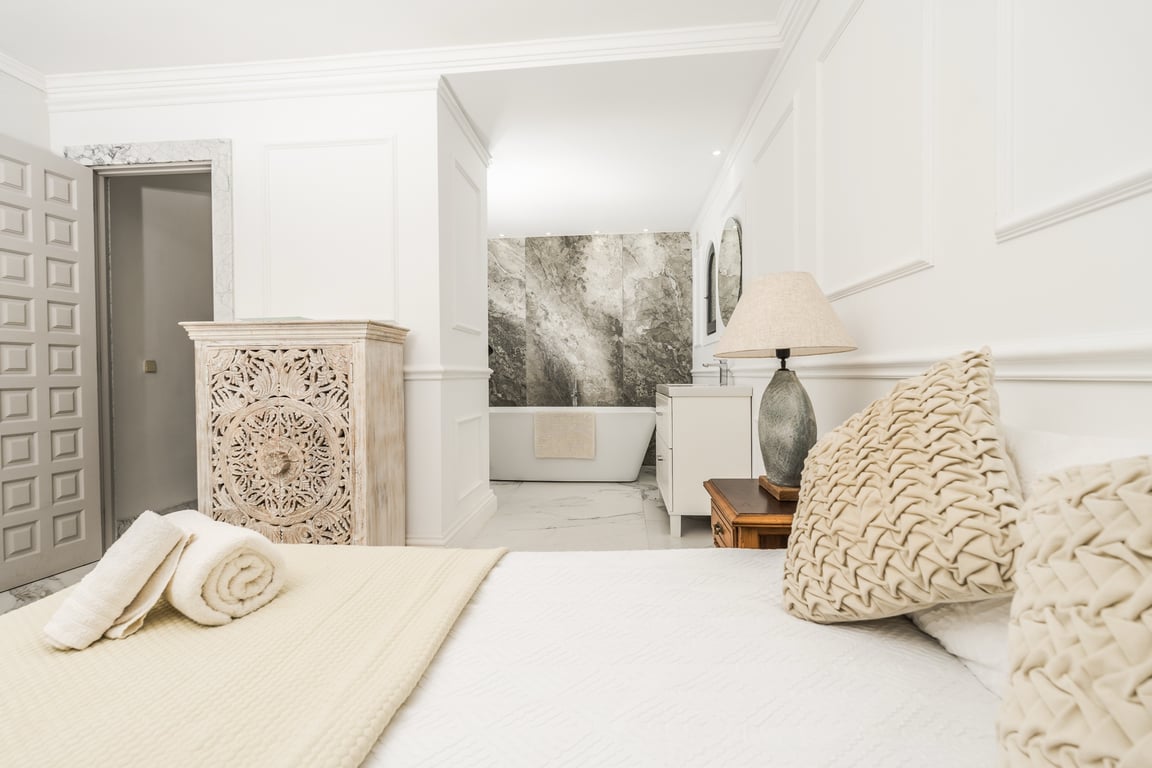 Master suite featuring an open-concept bathroom with a freestanding tub, marble accent wall, and elegant wall paneling.