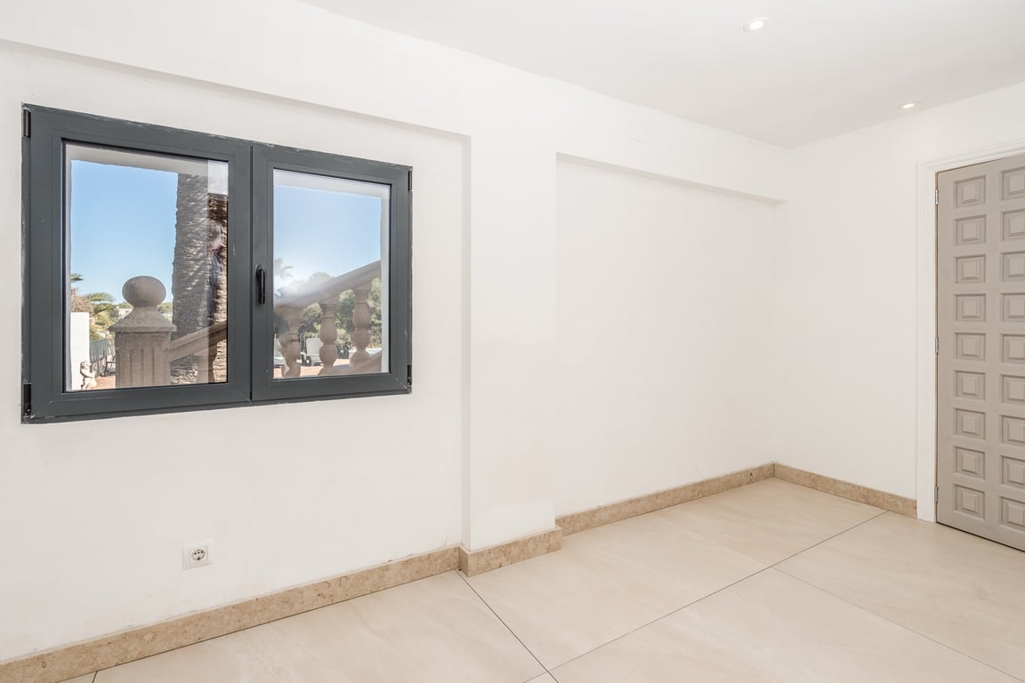Renovated room featuring natural stone flooring, recessed ceiling lights, and a dark aluminum window with views of the Mediterranean exterior.