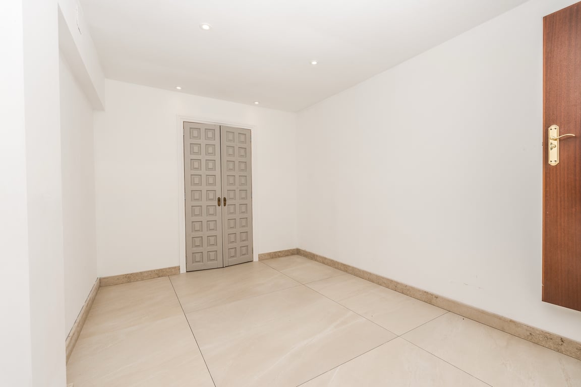 Spacious room featuring large-format marble flooring, recessed ceiling lighting, and decorative grey double doors with a unique geometric pattern.