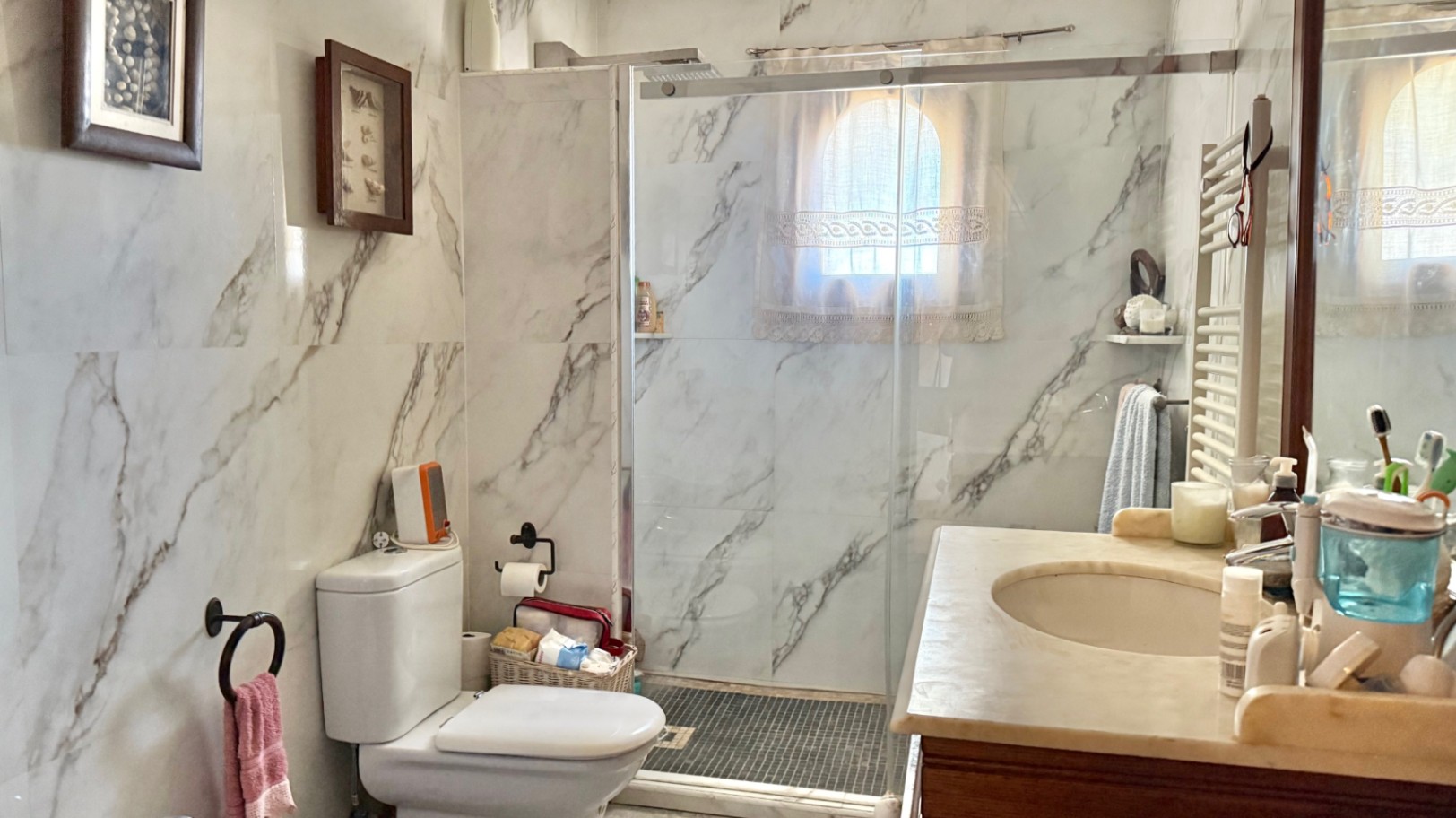 Bathroom featuring marble-effect wall tiling, a walk-in shower with a glass screen, and a vanity unit with a natural stone countertop.