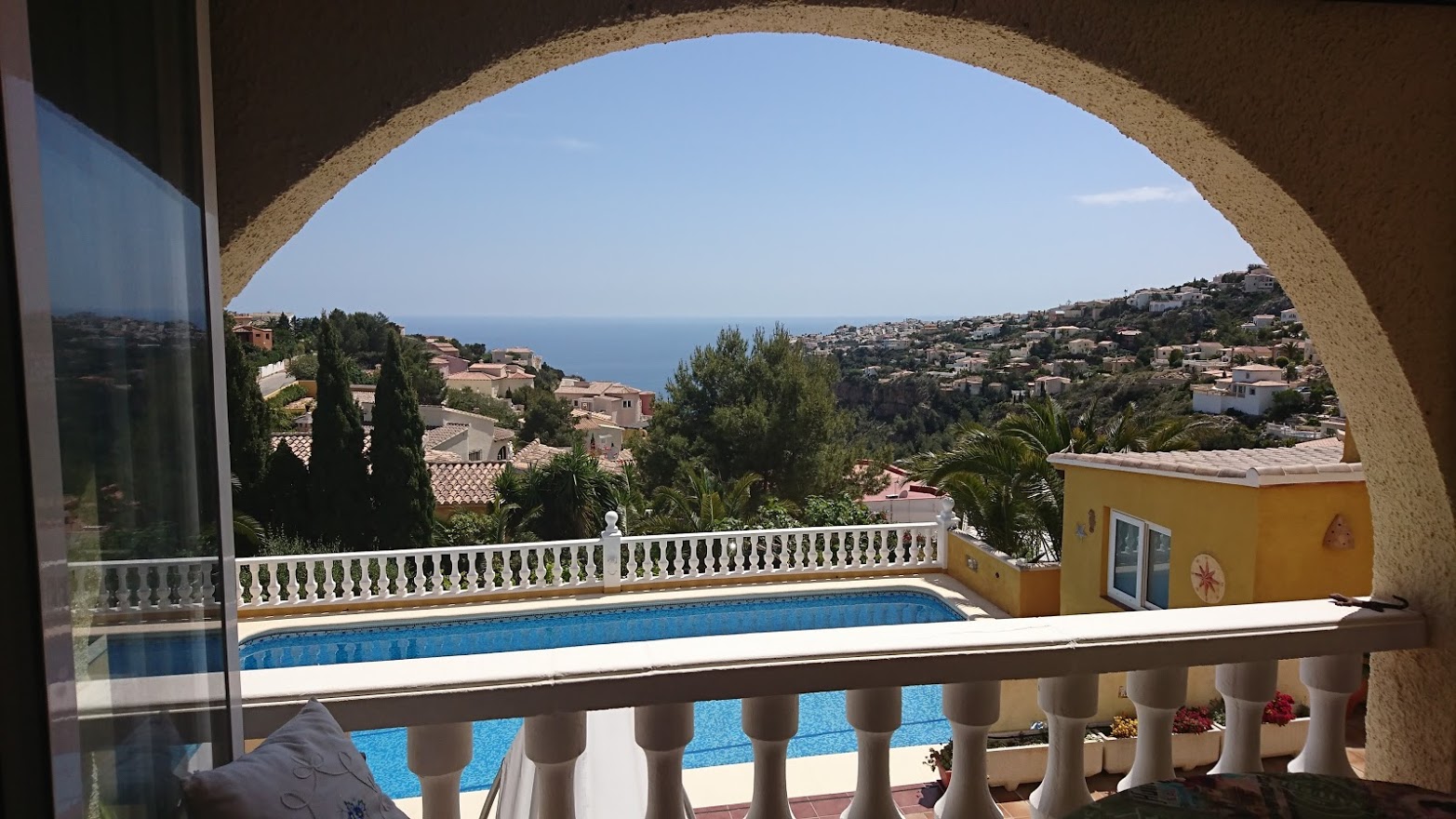 Panoramic Mediterranean Sea views framed by a traditional archway, overlooking the private swimming pool and white stone balustrades.