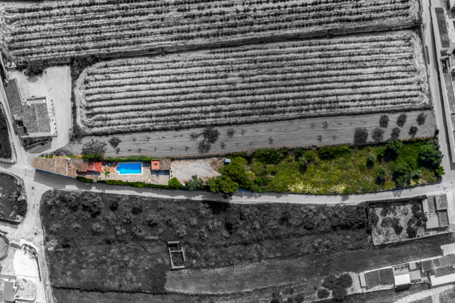 Aerial view of a finca with a pool in Teulada, surrounded by fields and greenery.