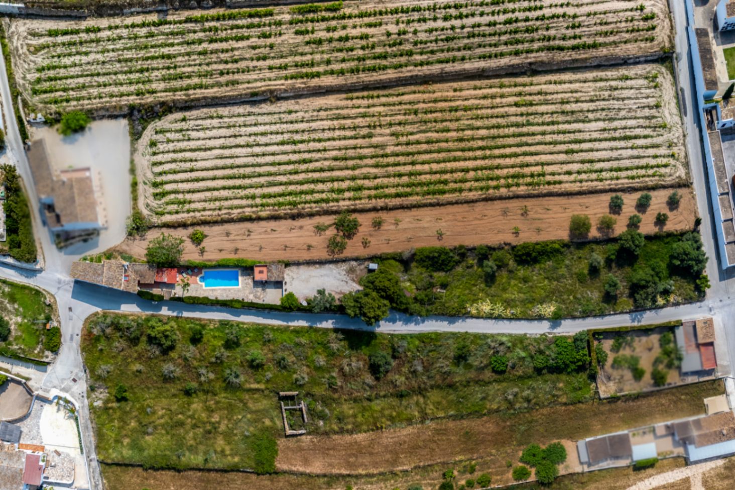 Aerial view of a rustic finca with pool in Teulada, surrounded by farmland and Mediterranean vegetation.