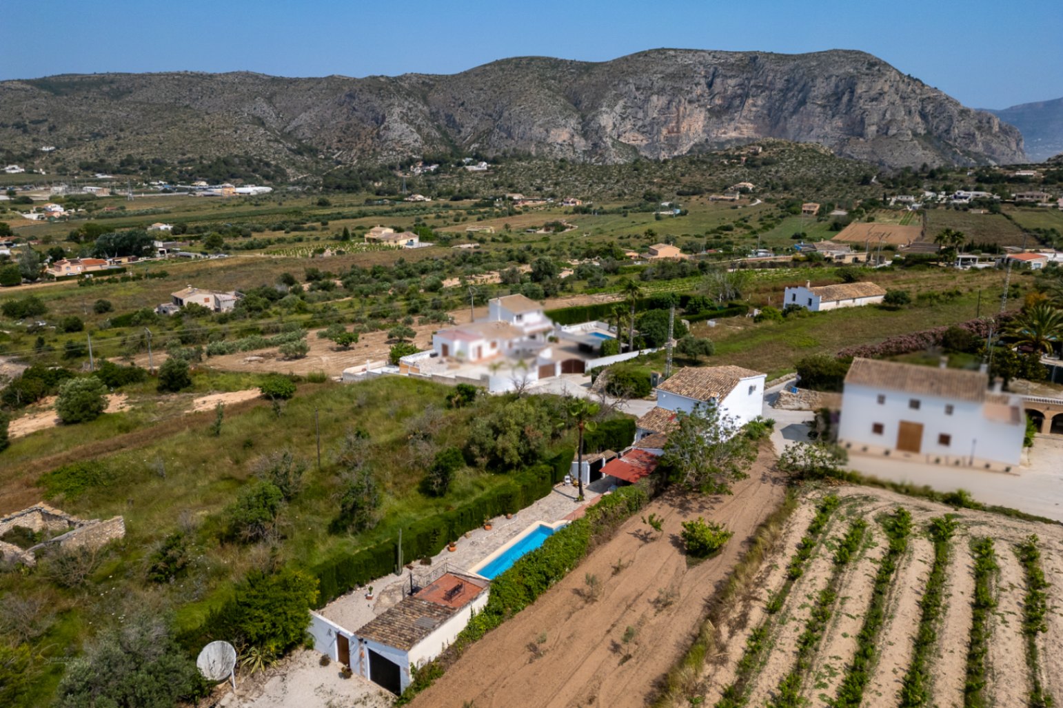 Aerial view of Teulada estate with elongated pool, mature garden, and mountain views.
