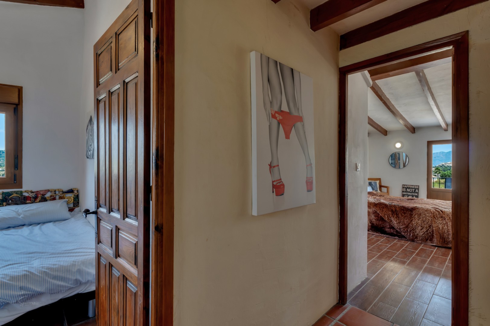 Hallway detail with wood doors, rustic tile flooring, and a modern art piece on the wall.