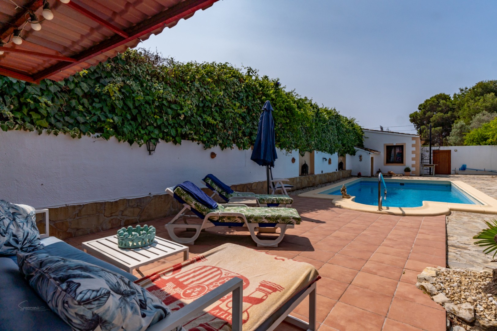 Pool view with sun loungers and vegetation-covered wall in Teulada.
