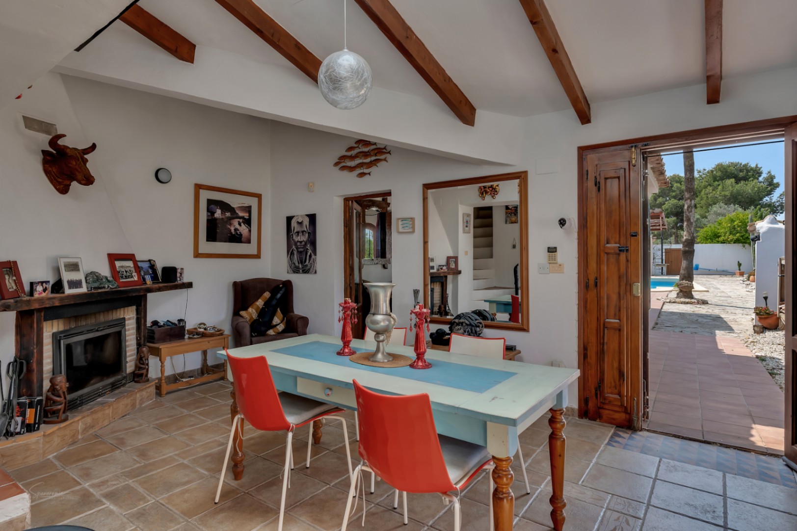 Rustic dining room with fireplace, wood beams, and garden access with pool view in Teulada.