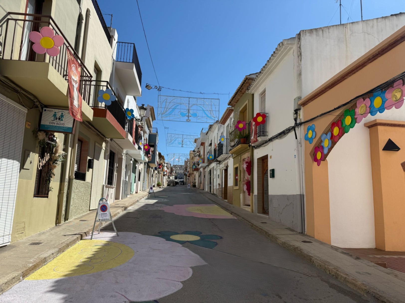 Teulada street decorated with painted flowers and hanging festive ornaments.