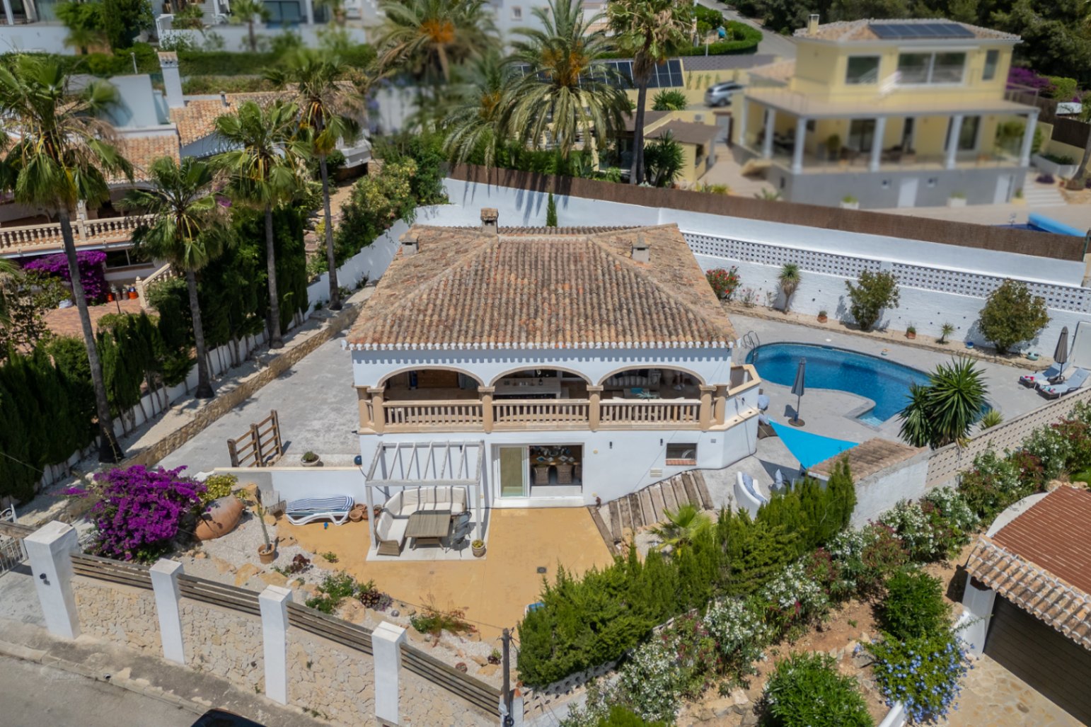 Aerial view of Jávea villa featuring a covered terrace, blue pool, and Mediterranean garden.