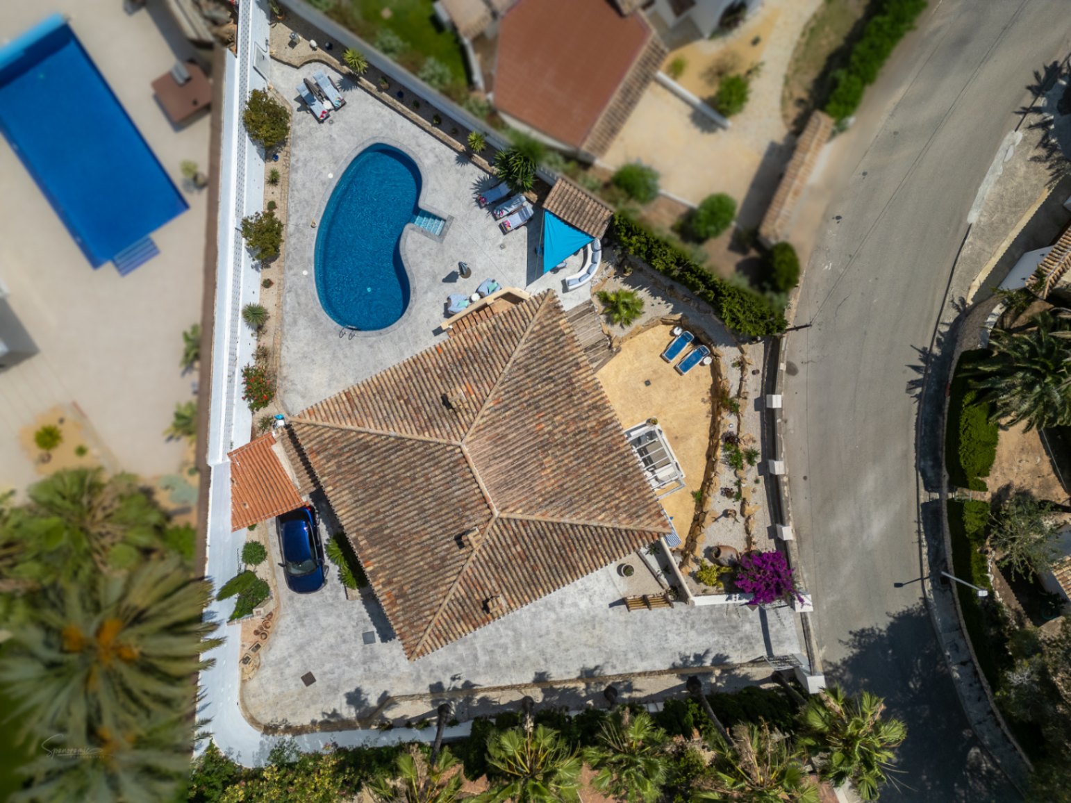Aerial view of villa with pool, terrace, and red tile roof. Private parking visible.