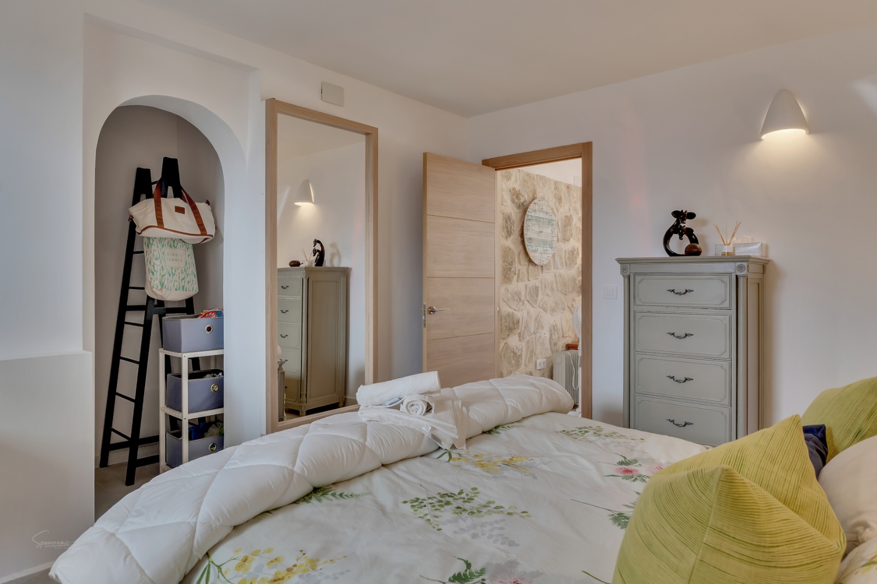 Bedroom detail with decorative niche, gray dresser, and floral bedding.